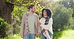 Interracial, couple and walking in park for love, care and relax on romantic date together in nature. Happy man, young woman or strolling in sunshine, spring garden or freedom of quality time outdoor