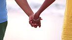 Couple, holding hands and love by beach in care for relationship, romance or compassion in nature. Man and woman with hand together for support on holiday, weekend or travel by the ocean coast waves