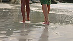 Couple, legs and walking on beach water together for holiday weekend, travel or bonding in nature. Feet of man and woman on a walk by waves, wet sand and ocean coast for vacation, bonding or relax