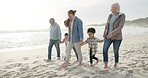 Happy, holding hands and interracial family on the beach for walking, bonding and holiday. Smile, talking and parents, grandparents and children with affection at the sea for a walk, travel and relax