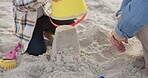 Hands, family and child with sand castle at beach for holiday, vacation or bonding fun. Man playing with girl and bucket toys for quality time, travel adventure and building for development at sea