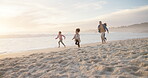 Family, children and running on a beach together on holiday or vacation for bonding fun. Man, woman and girl kids on sand for a race, chase or quality time at ocean for travel adventure and wellness