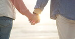 Couple, sunset and holding hands at beach for love, care and romance outdoor. Ocean, man and woman together with support in marriage, partnership and loyalty for bonding in relationship at sea coast.