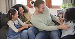 Tickle, parents and children laughing on sofa for bonding, quality time and relax in living room. Interracial family, playful and mom, father and kids at home having fun for joke, playing and cuddle