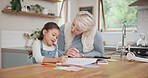 Grandmother helping a child with her homework in the kitchen for education studying at home. Creative, bonding and senior woman drawing an art picture with her girl grandchild at the family house.