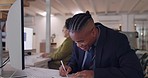 Computer, typing and a business man writing notes in office for research or solution. Tech, notebook and planning with african male employee reading information online for data analytics or database
