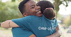 Friends, hug and happy while camping in nature, bonding or affection outdoor. People, embrace or care at campsite, smile and interracial black man and woman in love for counseling, support or comfort