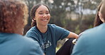 Volunteer, smile and a camp counselor group talking outdoor while planning at an outreach program for the community. Forest, happy or coffee with friends sitting outdoor in conversation about charity