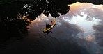 Nature, river and kayak from above with travel, reflection of sky and trees, relax on holiday adventure. Water, clouds and landscape, person rowing on lake for sport or vacation, aerial view of canoe