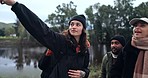 Friends, hiking and people at a lake in nature while pointing at view or destination for journey. Women and a man walking together as a group for a hike, trekking adventure or travel in countryside