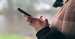 Hands, phone and social media with a person on a blurred background outdoor on an overcast day. Mobile, contact and communication with an adult typing a text message in the rain during winter