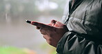 Hands, phone and communication with a person on a blurred background outdoor on an overcast day. Mobile, contact and social media with an adult typing a text message in the rain during winter