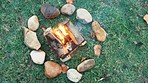 Bonfire circle, camp and outdoor in nature with stone, rock and safe on ground, grass and aerial closeup. Fire, flames and burn wood for heat, cooking or relax on lawn, field and woods for holiday