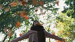 Woman, autumn and throwing leaves outdoor in a park with trees, freedom and fun in nature. Happy and excited person in warm clothes while playful on an adventure, travel or holiday in fall season