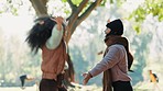 Friends, women and dancing in autumn leaves outdoor in a park with trees, freedom and fun in nature. Happy and excited people together in warm clothes while playful on adventure, travel or holiday 