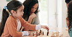 Family, mother and child playing chess for checkmate at home while teaching or learning board game. Latino woman and kid partner focus together to play for fun competition, development and bonding
