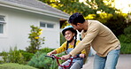 Dad, kid and teaching on bicycle outdoor in driveway of home for family support, help and play for childhood development. Happy father helping young girl on bike for learning skill, game and fun