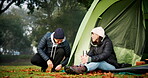 Couple, talking and tent outdoor for camping in nature with love, care and adventure. A young man and woman happy while at a camp site in winter for holiday, travel or vacation to relax in a forest