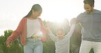 Family, happiness and walking with kid in nature for quality time on holiday or weekend. Couple, vacation and holding hands with son in outdoors for bonding with sunshine for relationship with care.