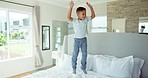 Fun, happiness and child jumping on bed with playful energy, freedom and excited in morning at home. Smile, holiday and happy kid in bedroom, weekend celebration and boy playing game in apartment.