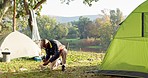 Camping, tent and black man setup in woods for shelter on outdoor holiday, vacation and adventure, Campsite, traveling and male person with hammer for pins for gear in nature, forest and countryside