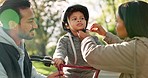 Helmet, bicycle and parents with child in park for cycling, having fun and adventure outdoors. Happy family, nature and mother, father and son with safety gear for riding bike, learning and training