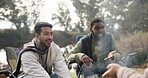 Friends, campfire and people talking outdoor in nature for fun, adventure and travel in woods. Camping, men group and funny story or discussion on camp site chair for holiday, bonding and freedom