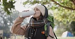 Explore, nature and woman drinking water while on a camp for an outdoor adventure or weekend trip. Happy, smile and young female person enjoying healthy beverage for hydration in the forest or woods.