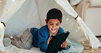 Tablet, relax and boy child in a tent playing an online game on the internet in the living room. Happy, entertainment and kid watching a movie, video or show on a digital technology in a blanket fort