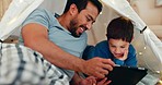 Relax, tablet and father in a tent with child tickling, playing and bonding at their home. Happy, smile and young dad watching movie, video or show with boy kid on digital technology in blanket fort.