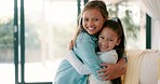 Happy little girl, hug and siblings for love, care or bonding together in living room at home. Portrait of sisters embracing childhood, unity or teamwork in happiness for youth and affection in house