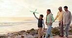 Family, walking and beach with boy, plane games and outdoor with love, care and bonding in nature. Grandparents, kids and airplane toys on vacation, holiday and playing together at sunset by ocean