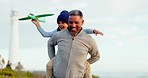 Man, child and beach with toy plane, games and outdoor with love, care and bonding by lighthouse. Grandfather, girl kid and airplane on vacation, holiday and playing together with piggy back by ocean