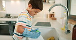 Learning, washing dishes or kid with dirty plate or gloves in kitchen sink at home for hygiene. Messy, child development or boy cleaning with liquid foam to disinfect or prevent the bacteria or germs