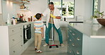 Cleaning, dad and child dance in the kitchen with a broom, sweeping and or fun housework in family home. Boy, learning to clean floor and father with happy, motivation and excited energy in house