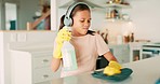 Girl child, headphones and spray for cleaning, table and dancing with cloth, music and singing in family home. Young kid, audio tech and chemical for dirt, bacteria and streaming web radio in house