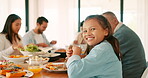 Thanksgiving, smile and a girl with her family eating food together while bonding in celebration. Love, lunch or brunch with the portrait of a female child and relatives at the dining room table