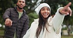 Couple, walking and pointing in park, outdoor or happy for adventure, exploring or date in winter. Woman, man and smile for search, direction or excited for holding hands, hiking and romance for love