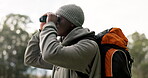 Black man, binoculars and backpack in travel to explore, sightseeing or looking for path or hiking trail in nature. African male person or hiker with vision or sight for adventure or journey outdoors