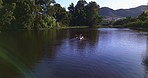 Water, trees and drone shot of people in kayak together, summer adventure and nature for sports, fun and hobby. Rowing boat, canoe and friends on river with trees, water and freedom on lake vacation.