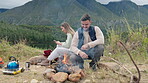 Campfire, happy couple and phone in nature for vacation, holiday and travel outdoor. Camping, smartphone and man and woman on social media together for adventure, hiking and trekking in countryside.