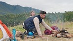 Couple, camping and fire with wood, outdoor and relax together in mountains, nature or forrest for holiday. Man, woman and flames on ground for heat, cooking and vacation in bush, field and morning