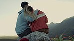 Hiking, mountain and sunset, couple hugging and relax on outdoor adventure, peace in nature from back. Trekking, rock climbing and love, man and woman with view of calm sky sitting on cliff together.