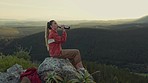 Hiking, view of mountain and woman drinking water, relax on outdoor adventure and freedom in nature. Trekking, calm rock climbing and hiker girl sitting with bottle, backpack and motivation to travel