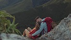 Mountain, sunset or couple kiss to relax outdoors together on adventure in nature from back for view. Love, hiking or romantic man hugging woman sitting on cliff on camping holiday, vacation or break