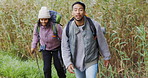 Talking, pointing and a hiking couple in nature for walking, trekking or travel in the countryside. Fitness, training and a man and woman speaking with direction in a field for adventure or journey