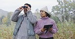 Couple outdoor, hiking and location on tablet, binocular and explore with trekking in nature and travel. People in forest, adventure and digital map, search environment with date and freedom together