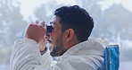 Man, binocular and bird watching in nature, hiking or camping with travel and relax outdoor in forest. Mist, male person and reaction to the environment, adventure and excited, search and explore
