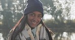 Nature, happy and face of a woman by a lake while on a winter weekend trip, holiday or adventure. Travel, freedom and portrait of an Indian female person with a smile in an outdoor forest or woods.