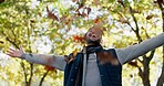 Happy, leaves and a man in nature during autumn, freedom and celebration of change in environment. Excited, travel and an Asian person with a smile in the woods or forest fall the fall season